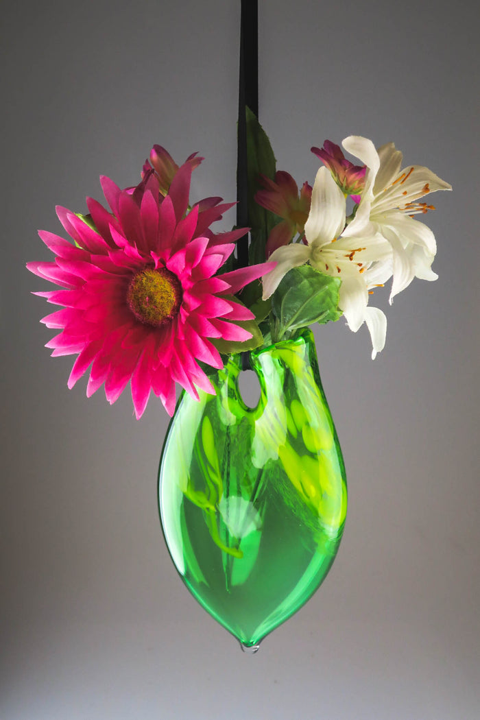 Deep cobalt blue hanging glass vase with a bright pink zinnia white lilies and pink accents.