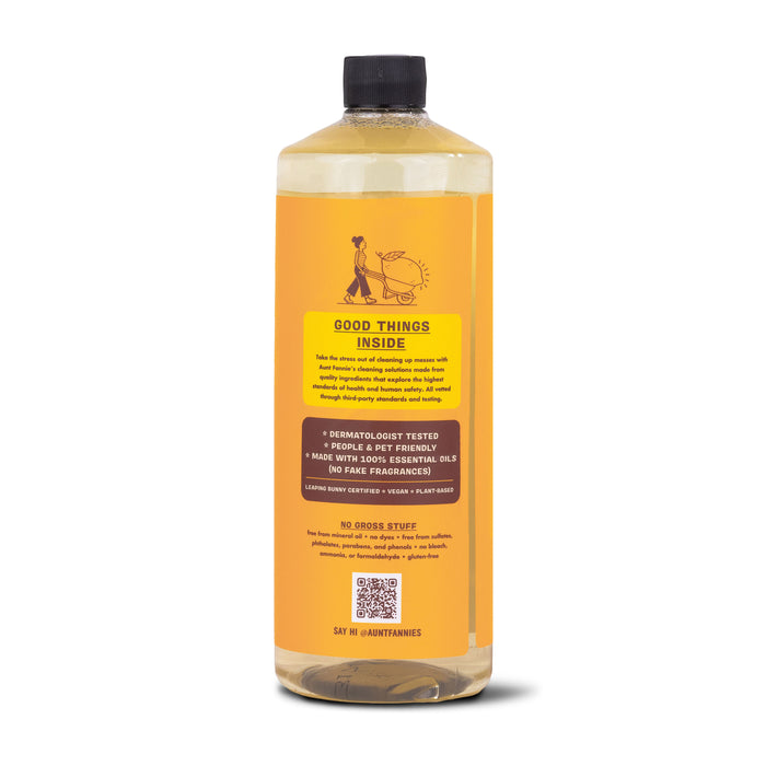 Aunt Fannies Hardwood Floor Cleaner comes in a bottle with an orange label emphasizing benefits like Good Things Inside. It includes phrases such as dermatologist tested, made with essential oils, vegan, and plant-based, highlighting non-toxic cleaning ideals.