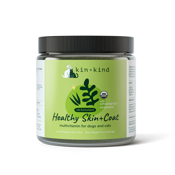 A jar of kin+kind Healthy Skin and Coat Powder Supplement for dogs and cats, featuring supergreens like wheatgrass and seaweed. The green label with leaf imagery highlights its vegan, organic nature. The jar contains 8 oz (226.8g) of nourishing goodness for your pets health.