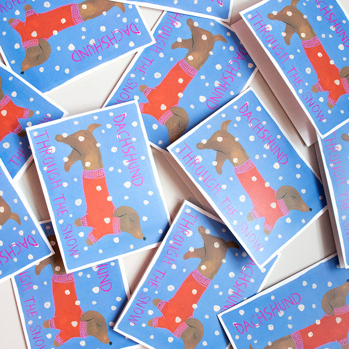 Supra Enduras Holiday Cards - Dog are scattered designs featuring a dachshund in a red polka-dot sweater with Dachshund Through the Snow in red on blue recycled paper, perfect for dog lovers.