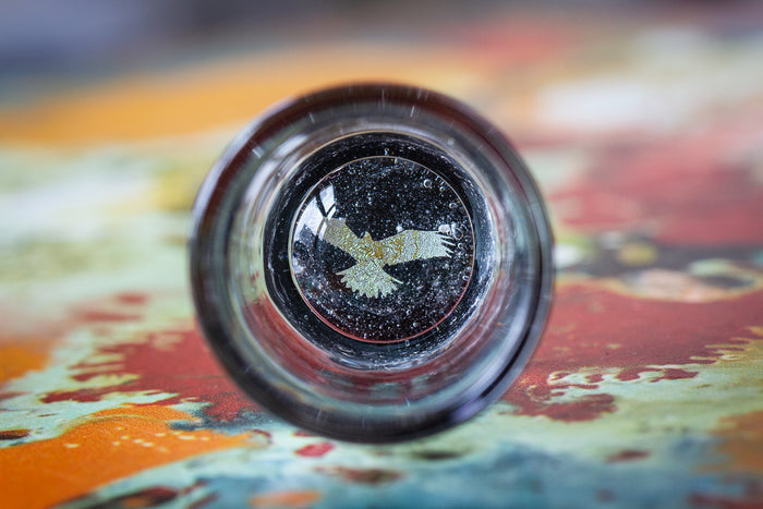 Hologram shot glass with cremation ashes spread on the bottom and a holographic symbol visible