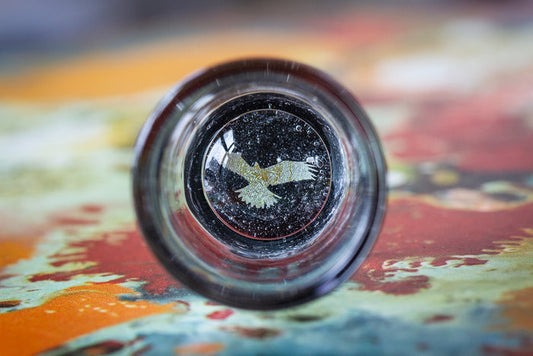 Hologram shot glass with cremation ashes spread on the bottom and a holographic symbol visible