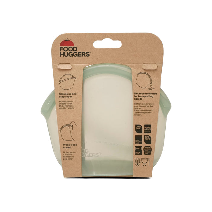 The Hugger Bag by Food Huggers comes in packaging with a green silicone cover and instructions on brown cardboard. It features sustainable materials, is dishwasher safe, easy to clean, but not suitable for transporting liquids.