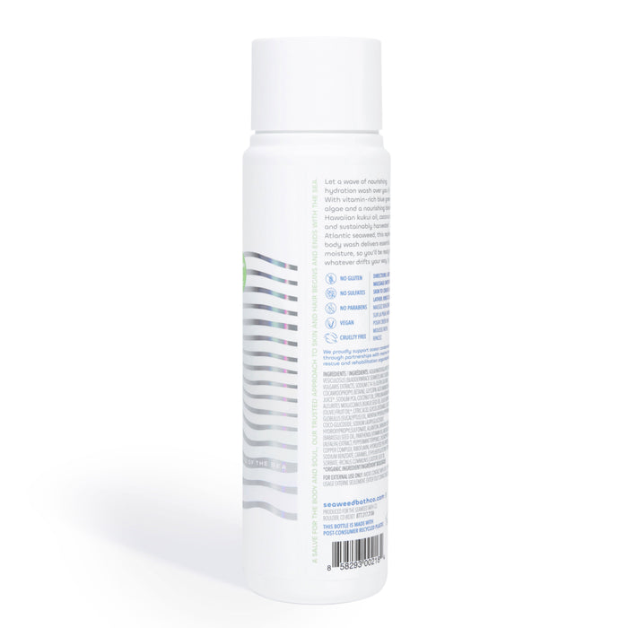 A white cylindrical spray bottle with colorful wave patterns and small blue text, featuring The Seaweed Bath Cos Hydrating Cleansing Body Wash enriched with nutrient-rich oils. The back label includes product details, a bar code, and website URL in light blue text.
