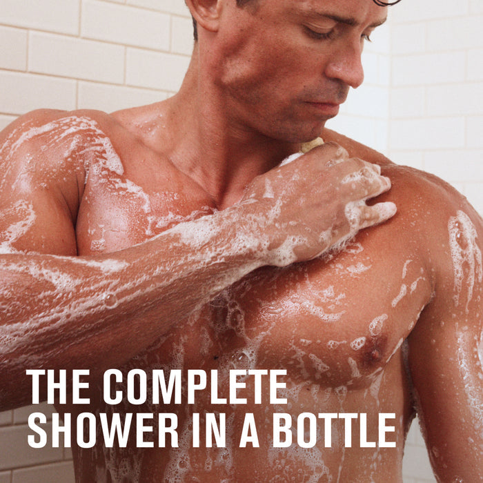 A muscular man with wet hair showers, lathering his chest and shoulder with Every Man Jack 3-in-1 All Over Wash. Coconut-derived suds cover his skin. White tiled walls frame the scene. Text at the bottom reads, THE COMPLETE SHOWER IN A BOTTLE.