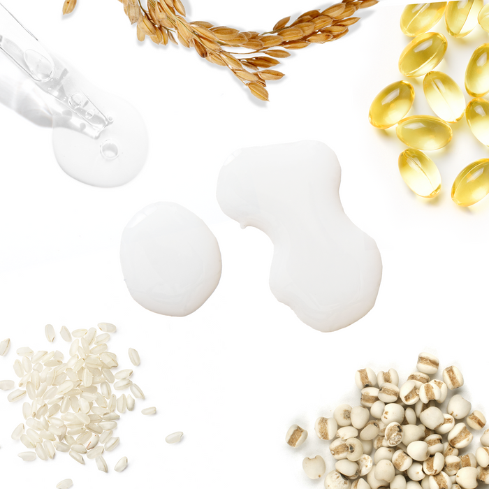 A flat lay image showcases Tree To Tubs Hydrating Milky Rice Toner for Dry & Dehydrated Skin, featuring a transparent dropper, rice bran water grains, millet, and golden capsules surrounding splotches of white liquid on a pristine background.