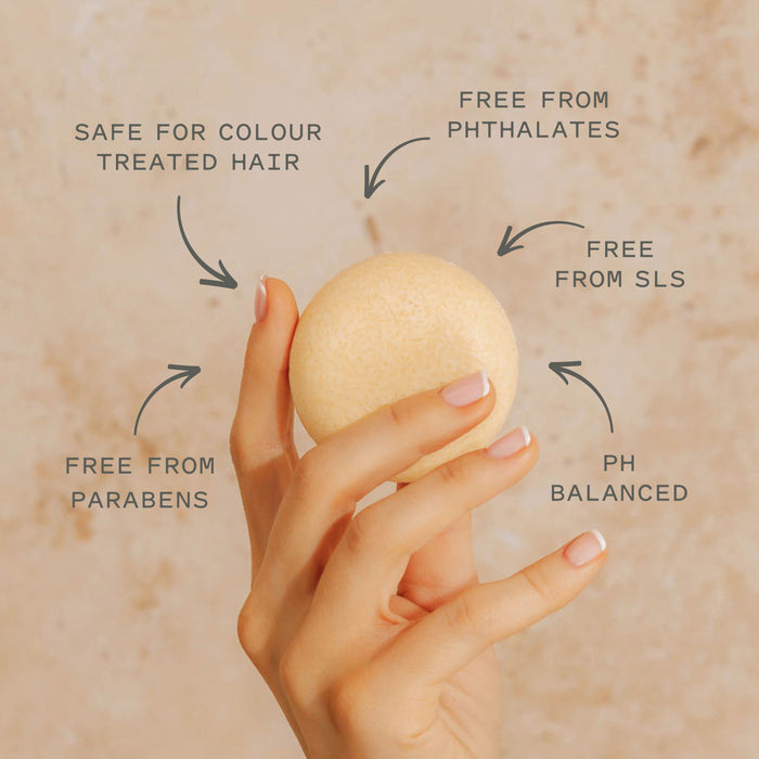 A manicured hand holds the Good Juju Body & Home Hydrating Shampoo Bar. Arrows highlight: "Safe for colour treated hair," "Frizz control," "Free from phthalates," "pH balanced," and "Free from parabens.