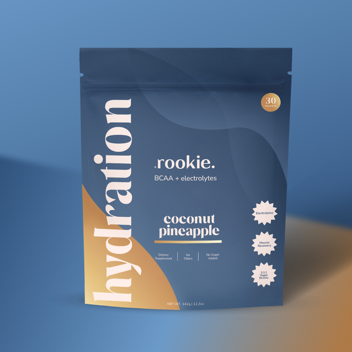 A blue and gold Rookie Wellness pouch labeled "Hydration Support + Electrolytes with BCAA" in coconut pineapple flavor. Features include large "hydration" text, icons for electrolytes, amino acids, no sugar added, and dietitian recommended.