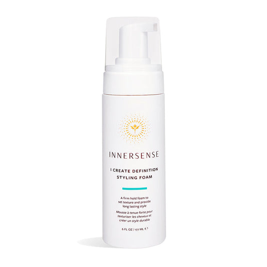 The Innersense Organic Beauty I Create Definition Styling Foam comes in a white 6 fl oz (177 mL) bottle with a pump dispenser and a gold circular design near the top. Infused with aloe leaf juice, it offers firm hold for long-lasting, frizz-free curls.