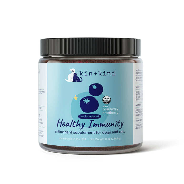 A jar of kin+kind Immunity Booster Powder Supplement for dogs and cats, enriched with cranberries and blueberries for urinary tract health. It is vet-formulated, USDA organic, hand mixed in the USA, and available in an 8 oz (226.8 g) jar.