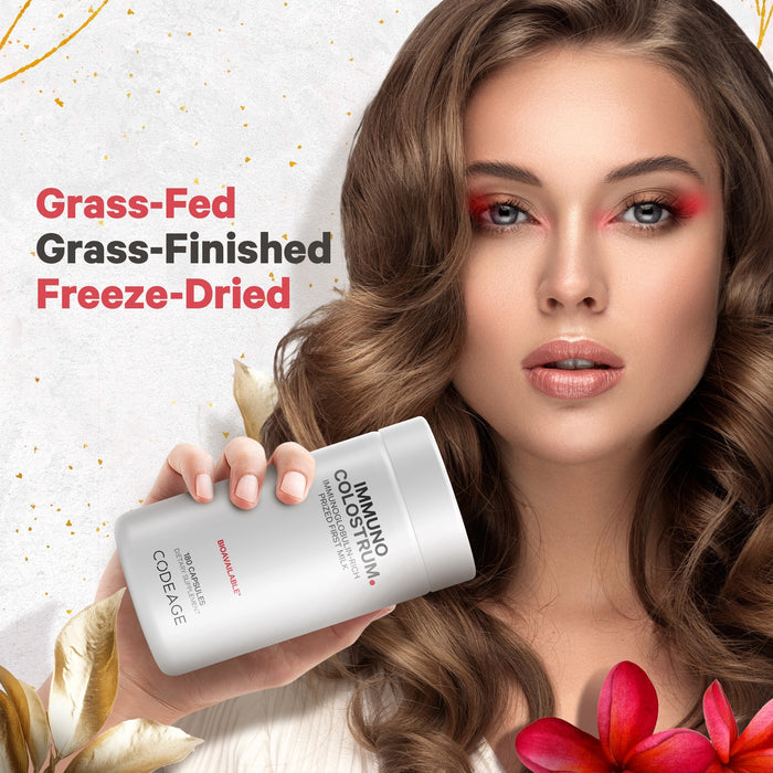 A woman with long, wavy hair holds a container of Codeage Immuno-Colostrum powder. Text next to her reads "Grass-Fed, Grass-Finished, Freeze-Dried." There are decorative flowers in the foreground.