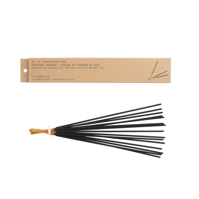 A kraft box labeled No. 02: Sandalwood Rose holds a tied set of black charcoal incense sticks. It features the elegant French brand P.F. Candle Co. Its warm teakwood and tobacco scent exudes serenity and sophistication.