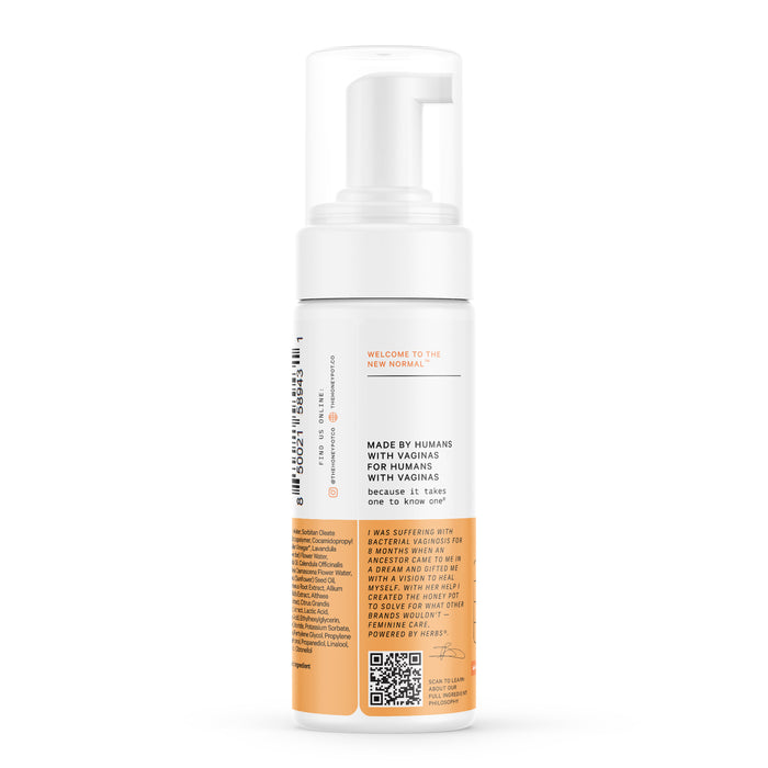 A white cylindrical pump bottle with an orange label details The Honeypot Companys Foaming Wash - Normal, featuring lactic acid for pH balance. The text states, Made by humans for humans with vaginas. A QR code is visible on a plain white background.