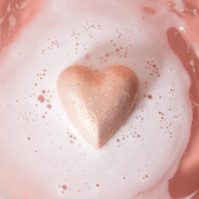 The Jasmine Gardenia Froth Bomb by Pacha Soap Co. dissolves in water, creating a spa-like foam. It turns the water a soft pink with rose clay and bubbles, offering a soothing and visually pleasing experience.