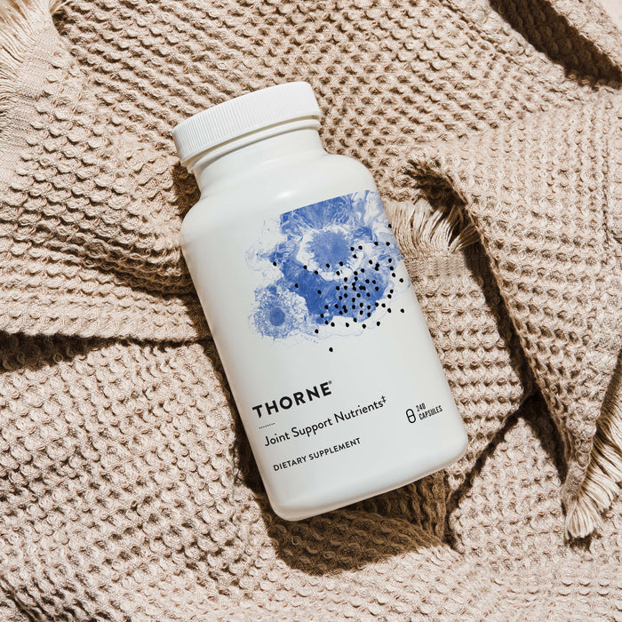 A white bottle of Thornes Joint Support Nutrients sits on beige fabric. The label showcases blue floral artwork, highlighting glucosamines role in joint care and promoting joint health.