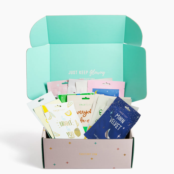 The open pastel box of the K Beauty Face Mask Set by FaceTory reveals a charming array of sheet masks decorated with leaves, stars, and moons. The vibrant packaging contains concentrated essence formulas and a reminder inside the lid: JUST KEEP GLOWING, making it an essential for self-care.