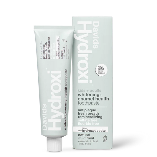 A tube and upright box of Davids Hydroxi Whitening + Enamel Health Toothpaste w/nano hydroxyapatite, labeled for natural whitening and enamel health for kids and adults. This fluoride-free toothpaste offers a mild mint flavor and the benefits of nano hydroxyapatite. The box stands upright beside the tube.
