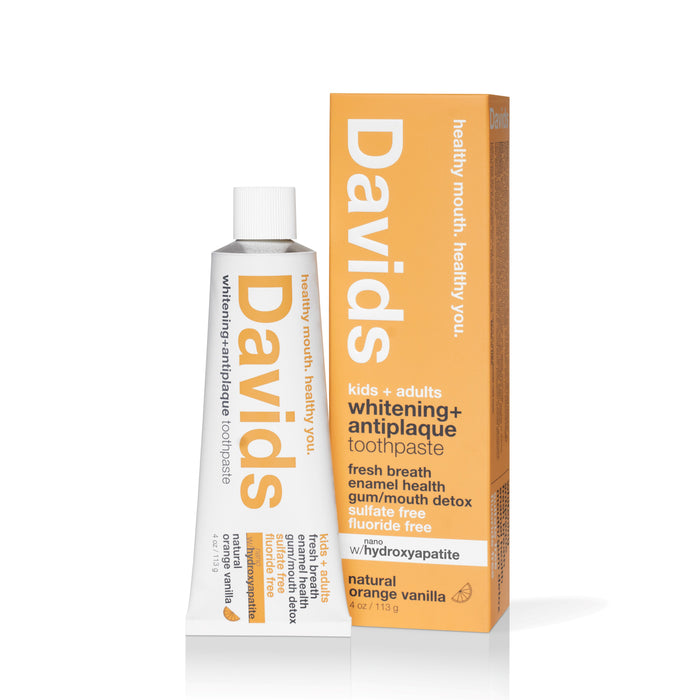 A tube of Davids Kids+Adults with nano-hydroxyapatite Toothpaste, featuring fluoride-free natural flavors in orange vanilla. The vegan formulas design highlights a clean white and orange color scheme that underscores its purity commitment.