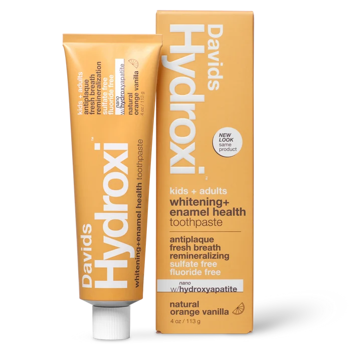 Davids Hydroxi Whitening + Enamel Health Toothpaste w/nano hydroxyapatite for kids and adults comes in a silver tube with an orange label and a box marked “whitening + enamel health.” The fluoride-free formula features ingredients for effective natural whitening, highlights its “natural orange vanilla” flavor, and is designed for both children and adults.