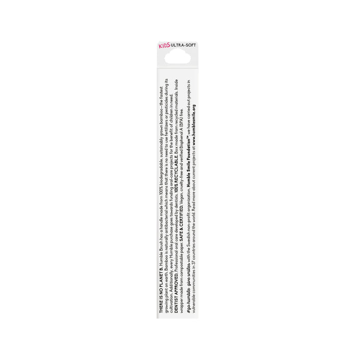 The image shows the back of a Kids Bamboo Toothbrush - Ultra Soft by The Humble Co. The packaging is white with black text detailing bamboo benefits and nylon bristles, with small, mostly unreadable instructions in multiple languages.