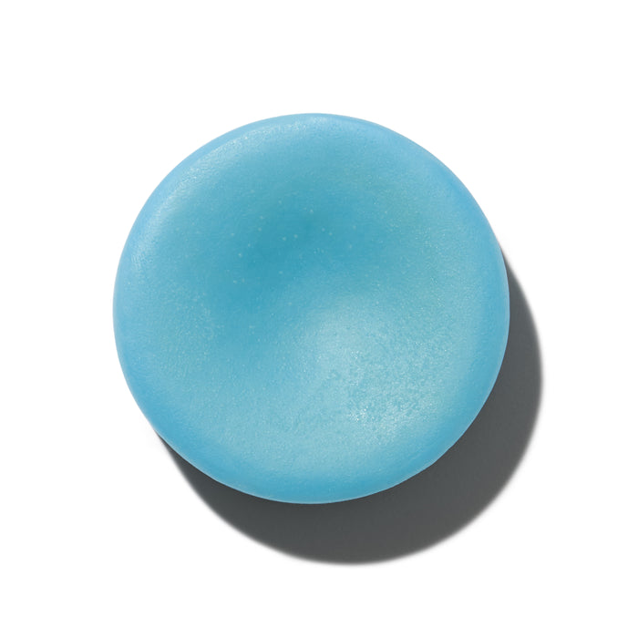 The NOT!CE Hair Co For Tangles Conditioner Bar is round and smooth with a shallow center indent. Ideal for kids hair, it gently detangles and nourishes delicate strands, casting a shadow on the white background.