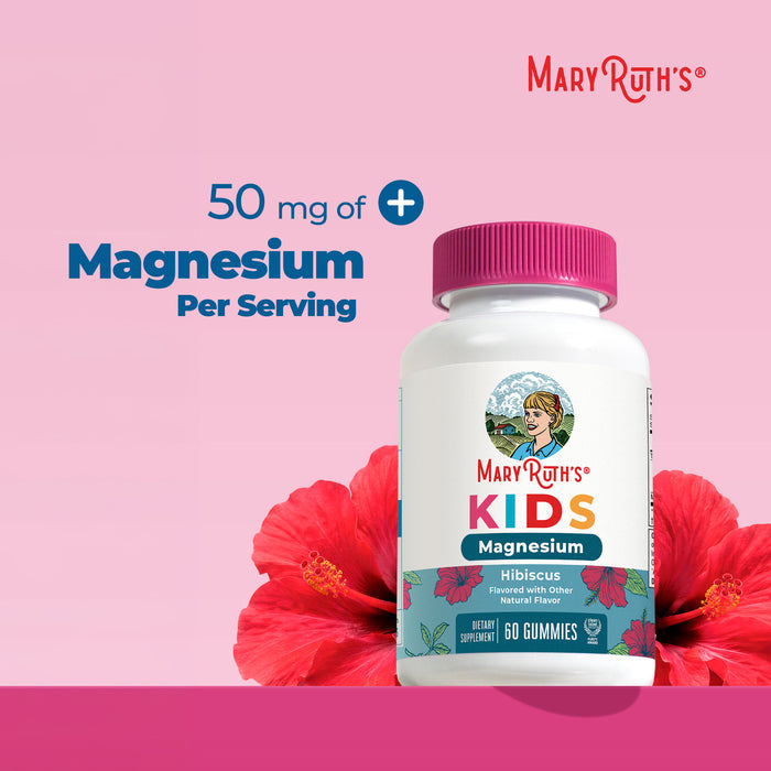 A bottle of MaryRuth's Kids Magnesium Calm Gummies (Hibiscus flavor) is placed next to hibiscus flowers. The label features 50 mg of magnesium per serving, promoting bone health and calm support for growing kids. The pink background displays the MaryRuth's logo in the top right corner.