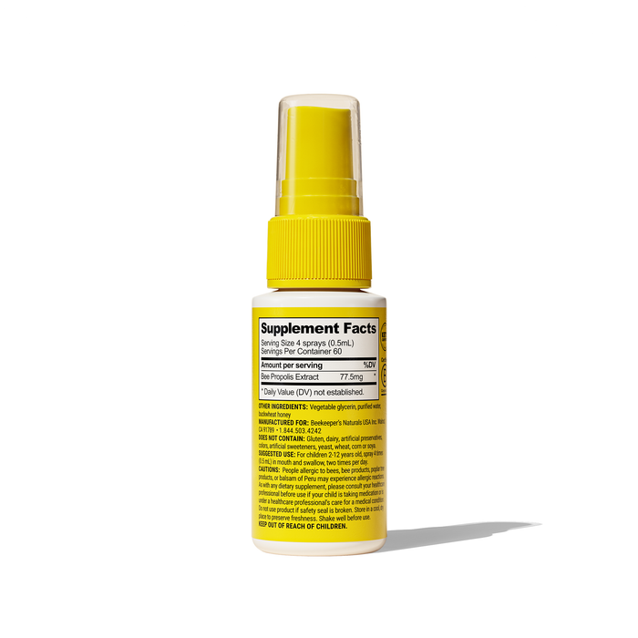 A yellow spray bottle with a white label, detailing Kids Propolis Immune Support Throat Spray by Beekeepers Naturals, features a complementing yellow cap. It reveals dosage and ingredients to support the immune system while its shadow dances across the white background.