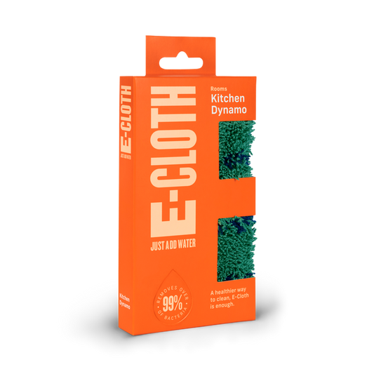 The E-Cloth Kitchen Dynamo Microfiber Scrubber is packaged in bright orange with a green scrubber visible through cutouts. It eco-consciously cleans by removing 99% of bacteria using only water for a healthier clean.