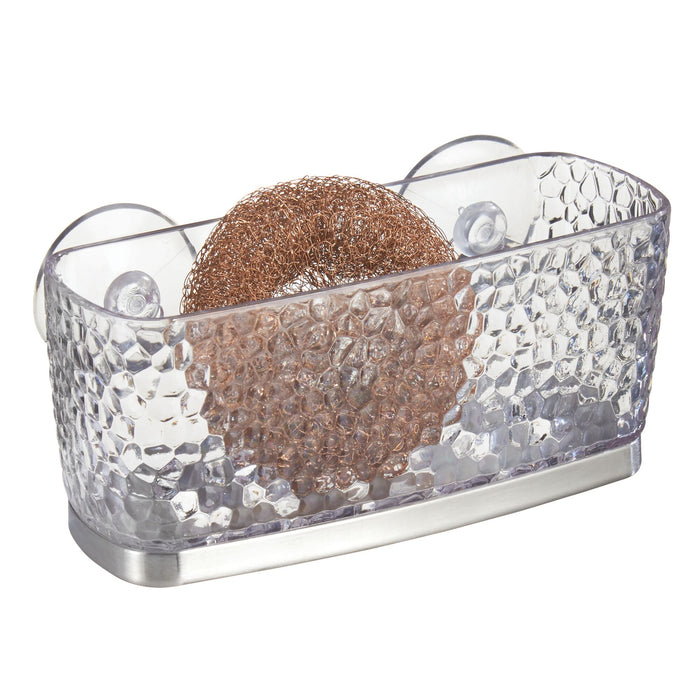 The iDesign Kitchen Sink Sponge Suction, crafted from recycled plastic, features a transparent, textured design with suction cups and a stainless steel base to hold a copper scrub pad.