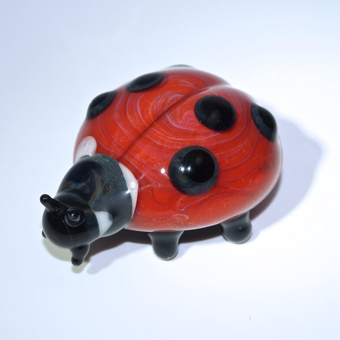 Full view of red glass ladybug cremains figurine on a white background