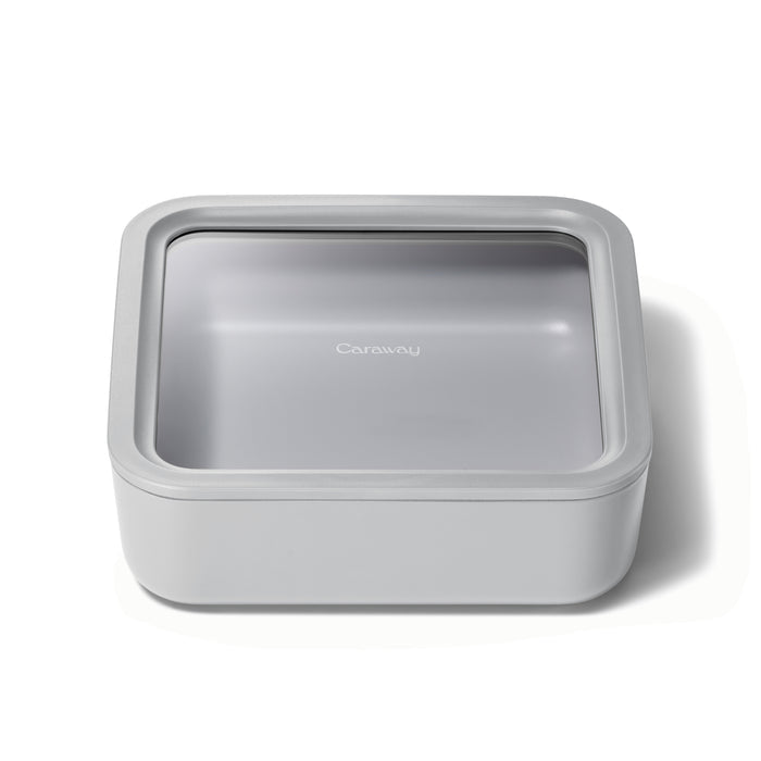 The Large Glass Food Container by Caraway is a square, light gray storage solution featuring a transparent lid with the brand label. Its ceramic-coated glass design is sleek and minimalist, ensuring non-toxic and ideal kitchen use.