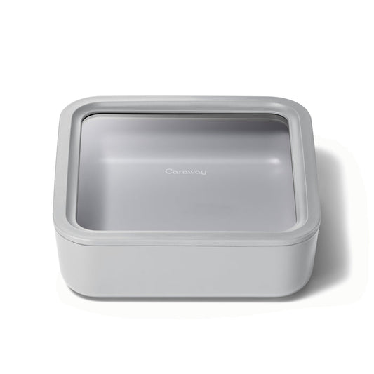 The Large Glass Food Container by Caraway is a square, light gray storage solution featuring a transparent lid with the brand label. Its ceramic-coated glass design is sleek and minimalist, ensuring non-toxic and ideal kitchen use.