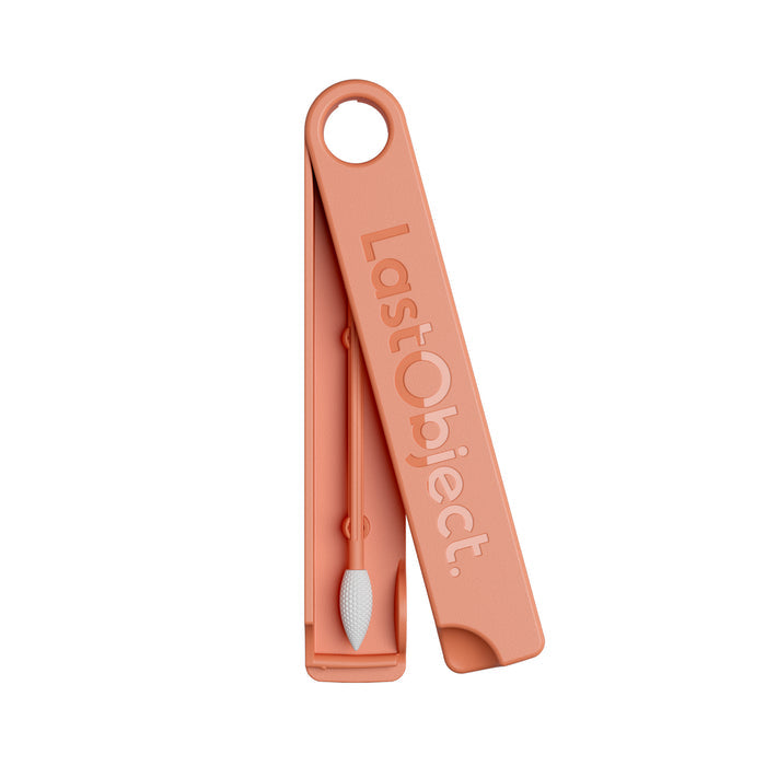 The LastSwab Beauty by LastObject is a peach-colored reusable cotton swab ideal for makeup. It features a textured white tip and comes in a matching rectangular case with a circular opening, embossed with LastObject, highlighting its eco-friendly design.
