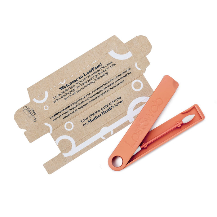 An orange LastSwab Beauty reusable ear cleaner by LastObject, housed in a matching case, is shown next to an open cardboard package. The packaging identifies it as a stylish, eco-friendly beauty product focused on sustainability.