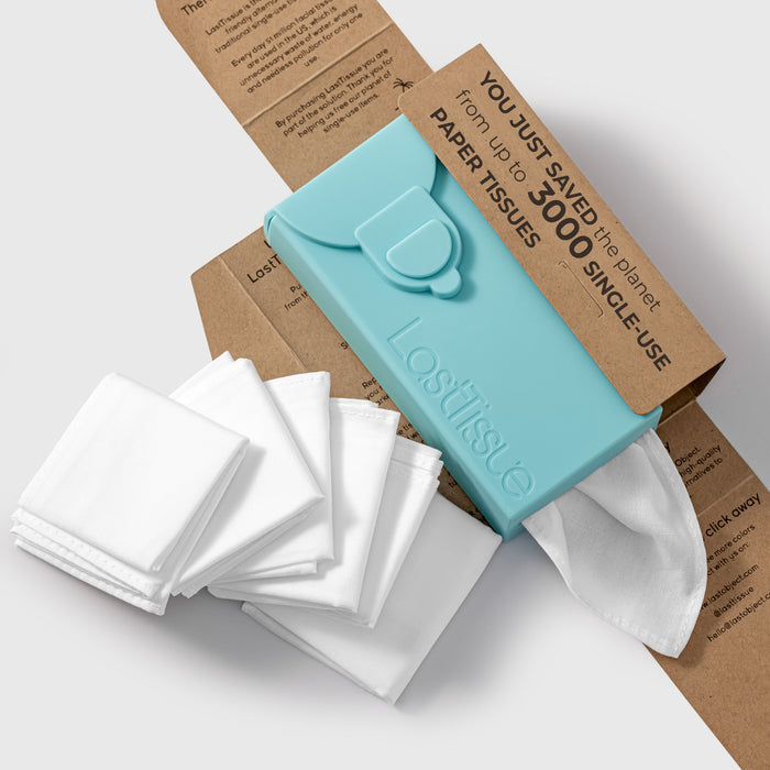 A teal LastTissue case by LastObject, set against a cardboard backdrop, holds eco-friendly, reusable white tissues made from organic cotton. The packaging emphasizes that it replaces up to 3,000 single-use tissues. Folded tissues are shown next to the case.