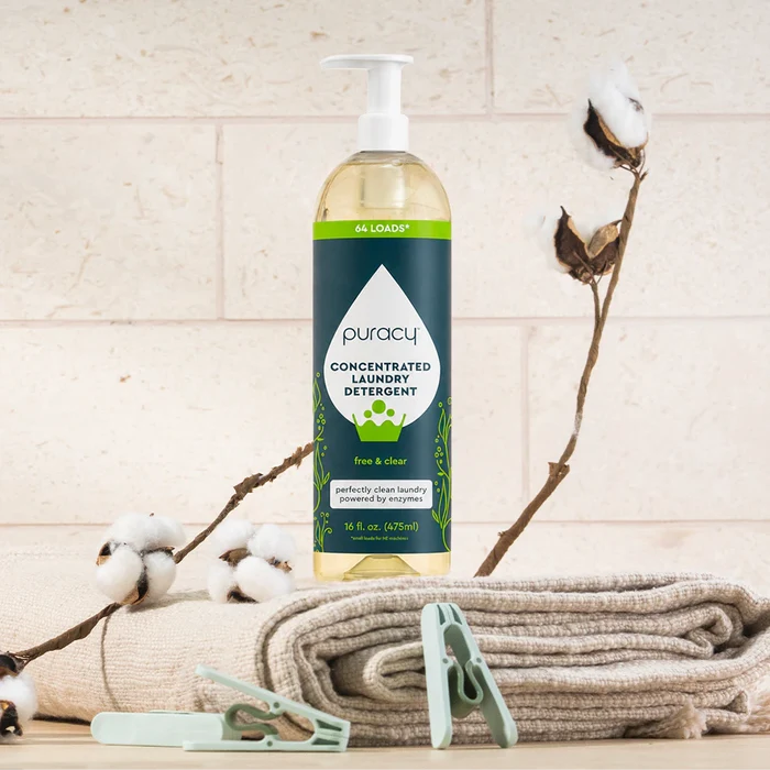 A bottle of Laundry Detergent (Concentrated, Sulfate-Free) beside folded towels and cotton branches.