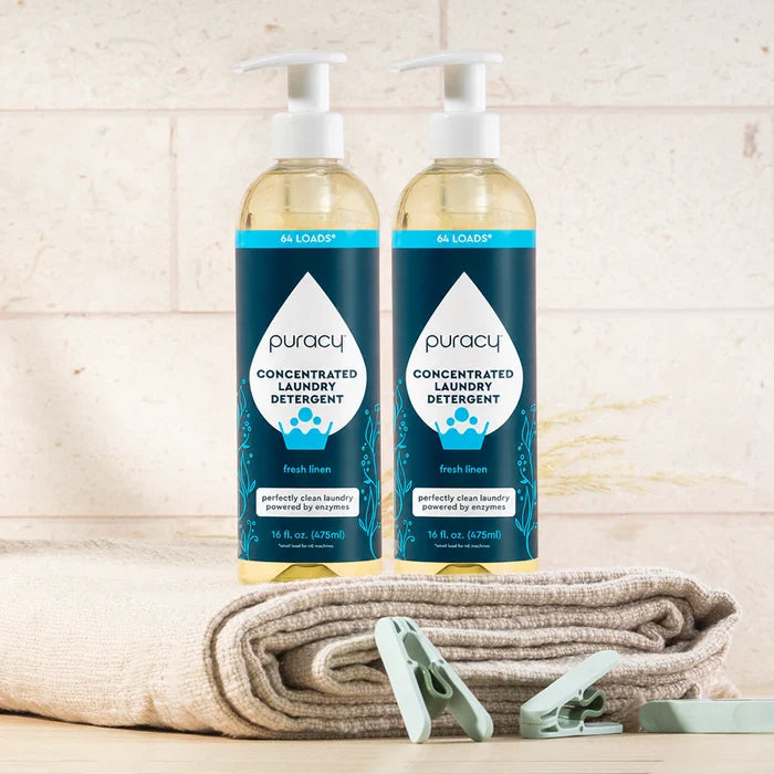 Two bottles of Laundry Detergent (Concentrated, Sulfate-Free) on towels with clothespins near tiles.