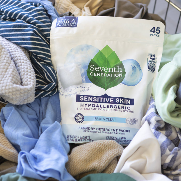A pack of Seventh Generation Laundry Detergent Packs - Sensitive Skin rests on assorted clothes, showcasing its plant-based formula effective in cold water and suitable for sensitive skin.