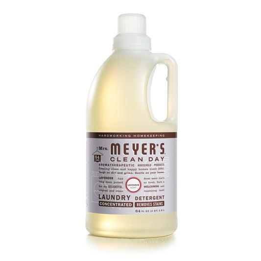 A 64 fl oz clear bottle of Mrs. Meyers Laundry Detergent in lavender scent, with an off-white cap and a label featuring purple and brown text, embodies refreshing cleanliness.