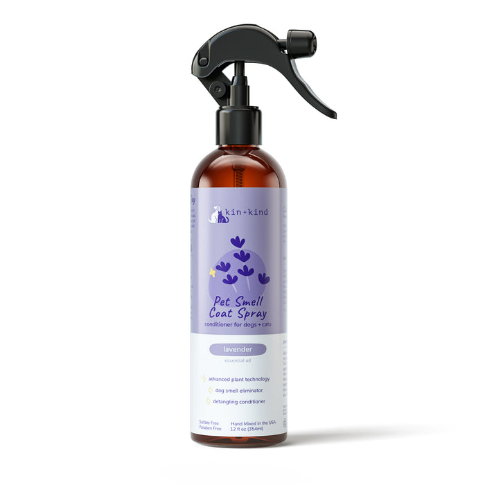A 12 fl oz kin+kind Lavender Natural Coat Spray for Dog & Cat in a brown bottle with a black nozzle features lavender illustrations. It functions as an odor eliminator and detangling conditioner, providing peace of mind with natural pet care.