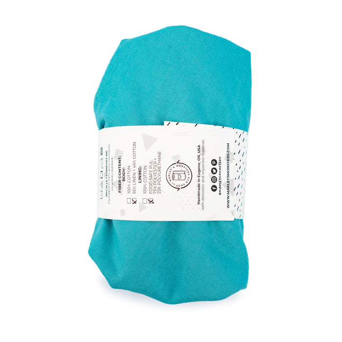 A rolled-up Aqua Linen Bowl Cover Bundle from Marleys Monsters, a sustainable kitchen essential, is secured with a chic white label detailing its specs, washing instructions, social media icons, and promoting it as a stylish reusable alternative.