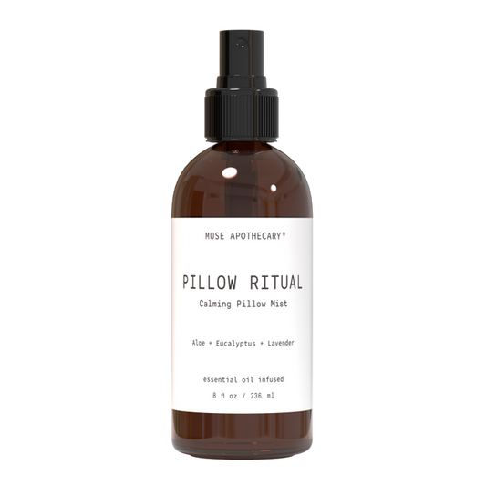The Muse Apothecarys Linen, Pillow and Fabric Spray in a brown bottle features aloe, eucalyptus, and lavender oils. It comes with a black nozzle and contains 8 oz (236 ml).
