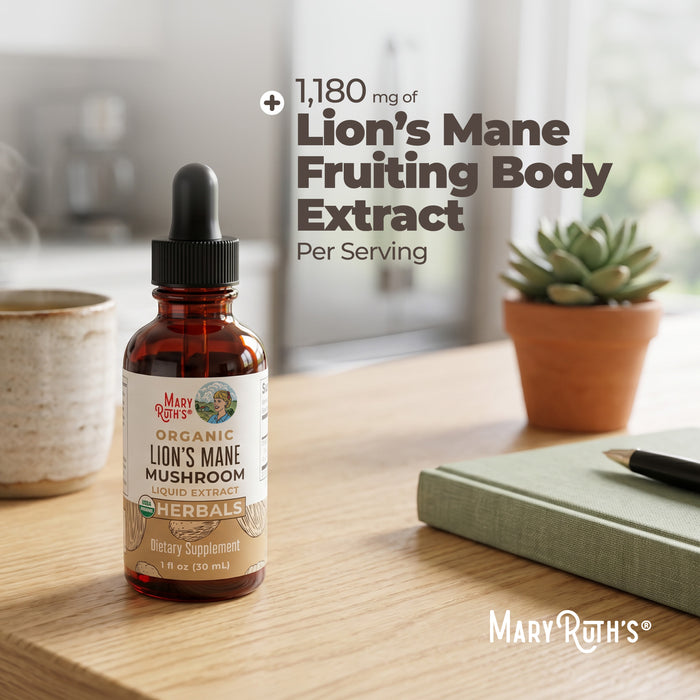 A bottle of MaryRuth's Lion's Mane Drops with a dropper sits on a wooden table next to a notebook, pen, and small potted plant. Text: “1,180 mg Lion’s Mane Fruiting Body Extract per serving for brain health.”.