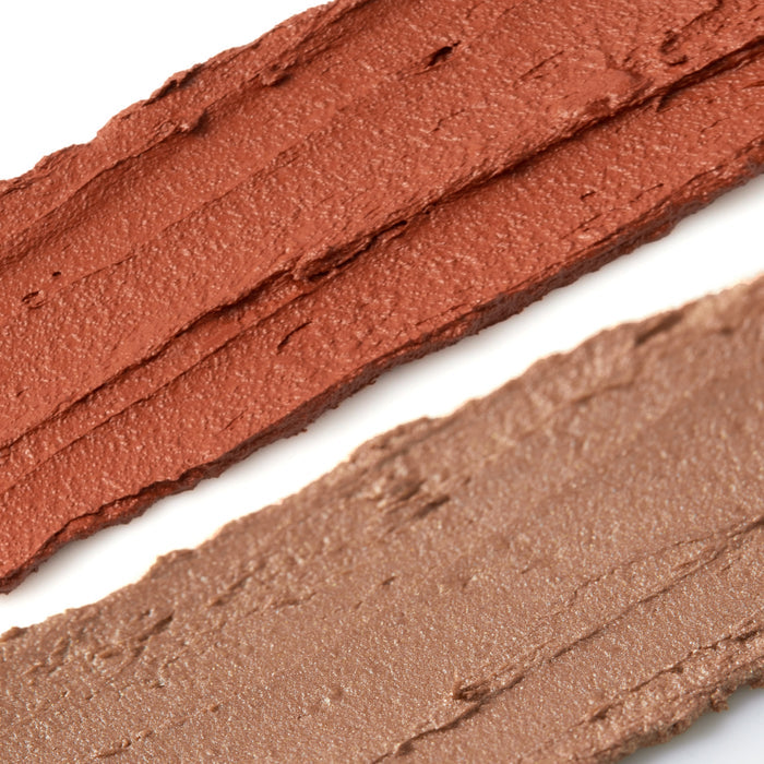 A close-up of two smudged vegan lipstick swatches on white displays a warm terracotta on top and a muted taupe below, both with creamy textures and slight sheen, reminiscent of Axiologys Balmie Duo.