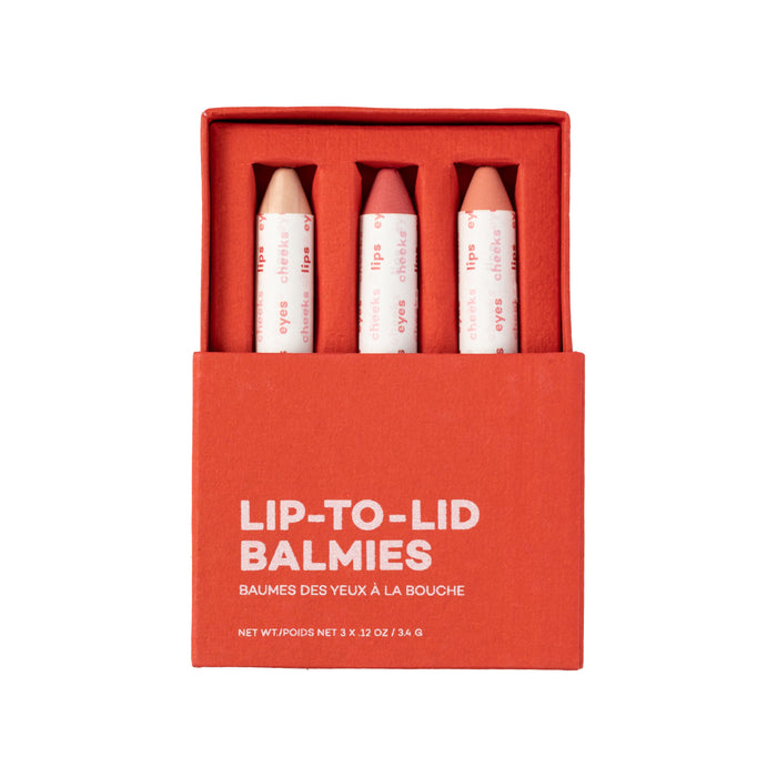 Axiologys Balmie Trio comes in a red box and includes three vegan, multi-use crayons in shades of pink and nude. Each crayon has a white paper wrapper with red text, perfect for versatile beauty looks.