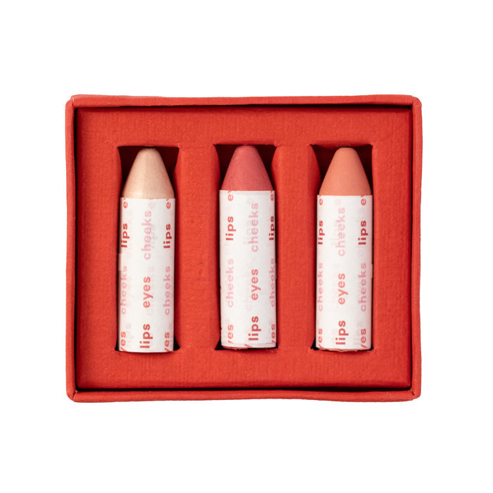 The Axiology Balmie Trio features a set of three vegan multi-use pastel crayons in a chic red box, each wrapped for lips, eyes, and cheeks, and nestled snugly in their own slots.