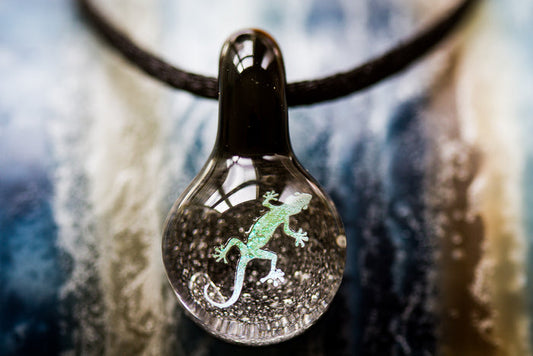 Lizard hologram pendant inside a clear glass teardrop with a dark top, suspended on a black cord