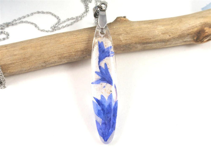 Close-up of crystal resin cornflower pendant with blue petals and a silver chain.