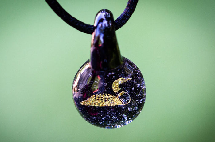 Loon hologram glass pendant with cremation ash and a gold loon silhouette on a black cord