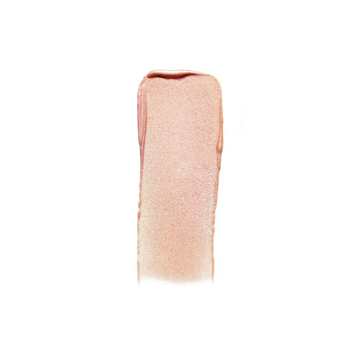 A swatch of RMS Beauty’s Champagne Rosé Luminizer, a shimmery light pink cream highlighter, is brushed in a rectangular shape on a white background, adding a subtle glow.